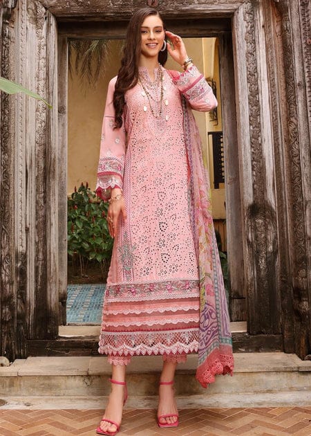 Woman in a pink embroidered traditional outfit standing in front of a wooden door.