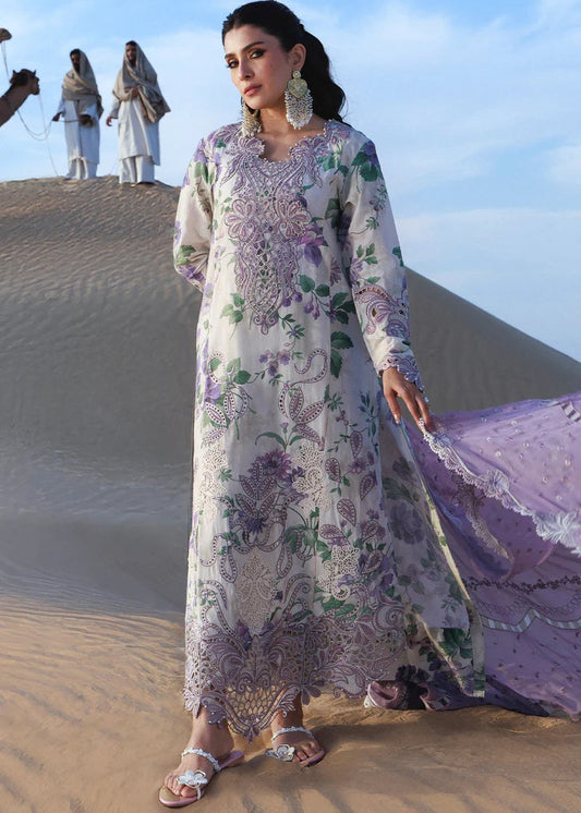 Woman in a floral dress standing on sand dunes with people in the background