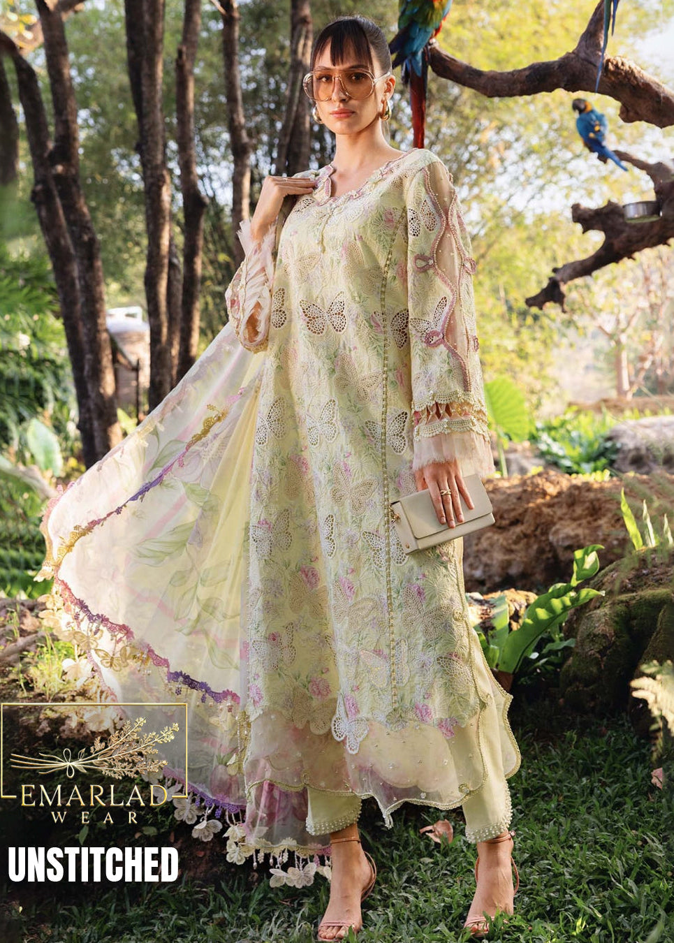 Woman in a light-colored embroidered outfit standing in a natural setting with 'Emarlad Wear' branding.