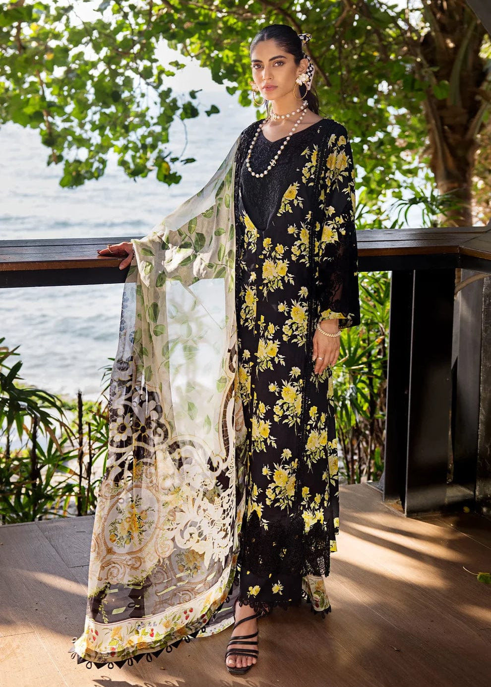 Woman in a floral dress standing by a railing with a scenic background