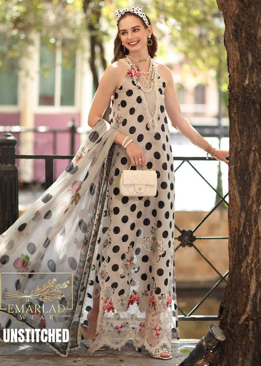 Woman in a polka dot dress with floral accents holding a matching shawl, standing outdoors.