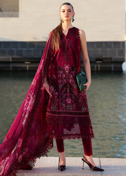 Woman in a burgundy embroidered outfit standing by a body of water.