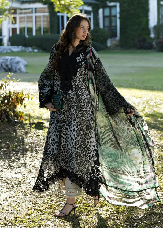Woman in a long, patterned coat standing outdoors with a house and garden in the background